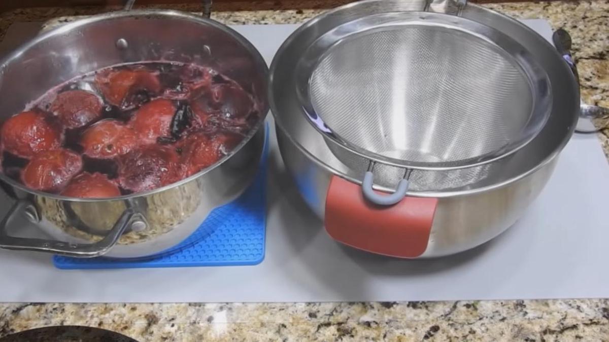 Сливы в кастрюле и дуршлаг на миске