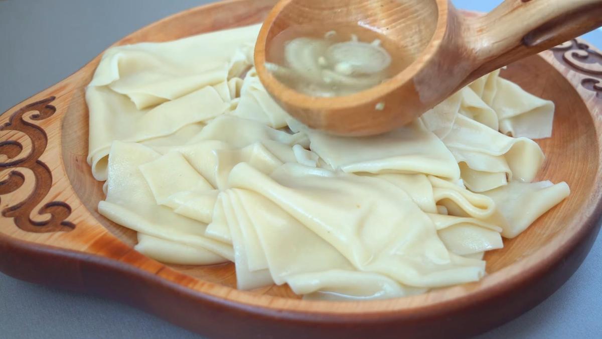 Сочни на деревянном блюде, политые куриным бульоном с луком