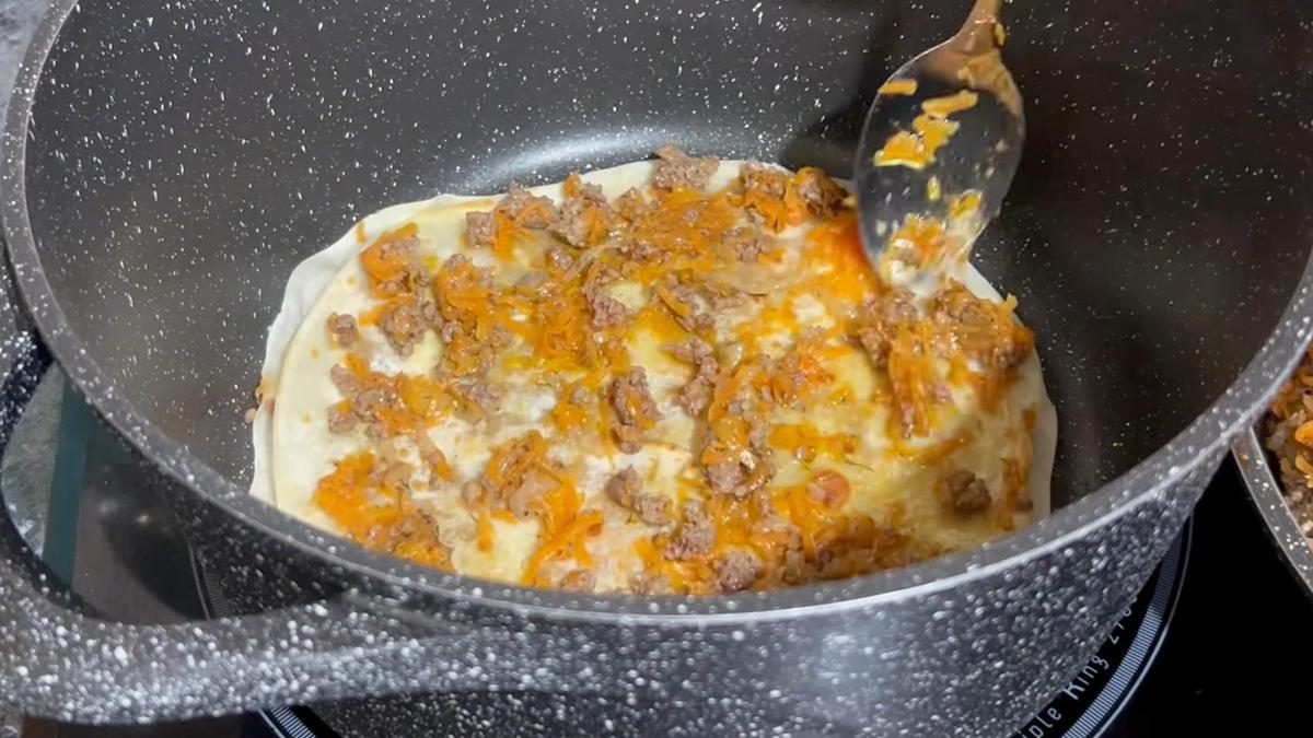 В казан выкладывают лепешку и мясной фарш с овощами