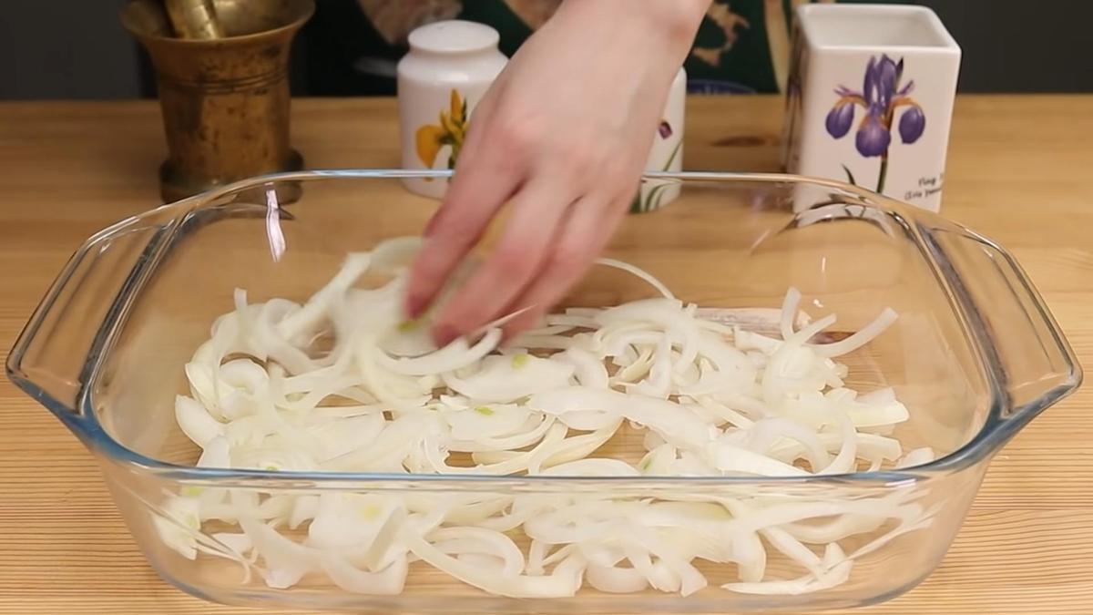 Нарезанный полукольцами репчатый лук в форме для выпечки