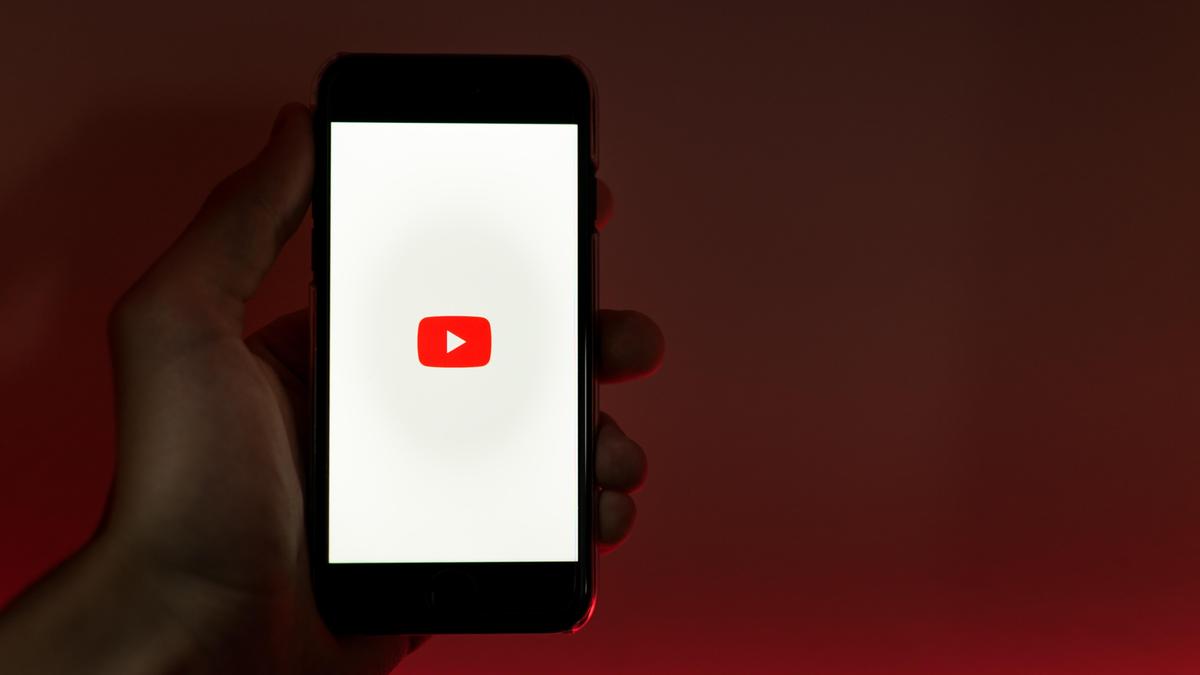 Человек держит в руках смартфон с включённым Youtube