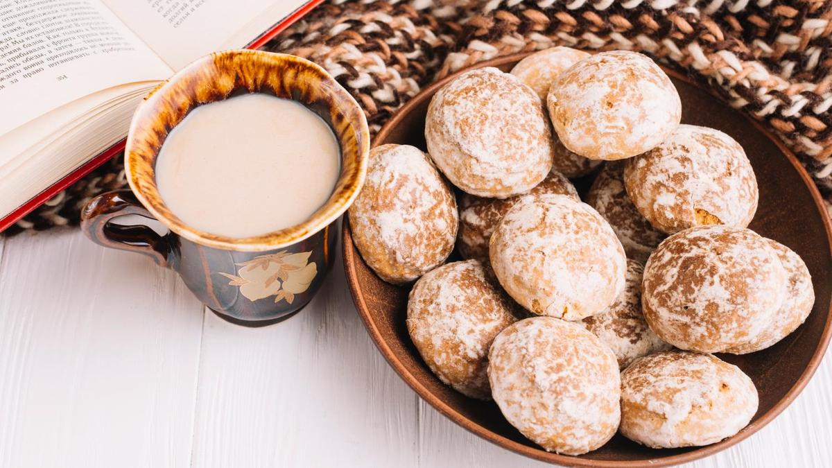 Медовые пряники в глазури на тарелке рядом с кружкой молока