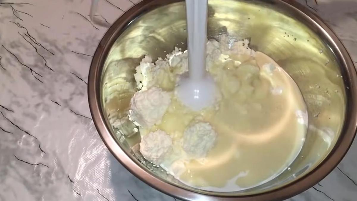 В железной миске творог со сливками и сгущенкой, который взбивают блендером