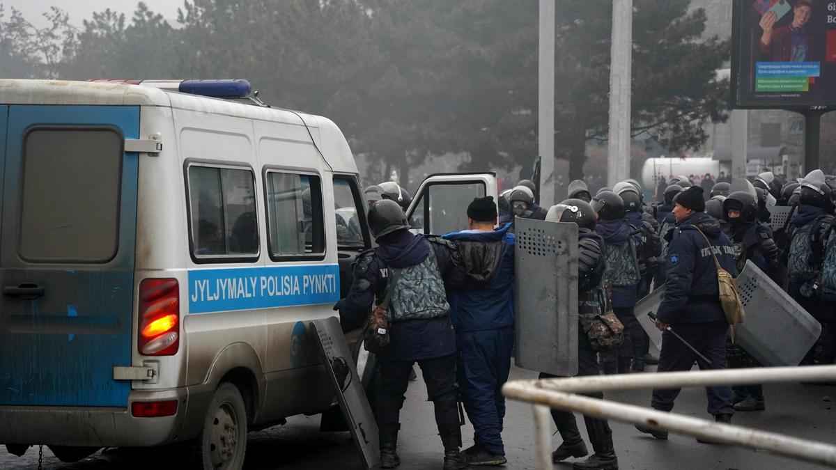 Полицейские заводят задержанного в служебное авто