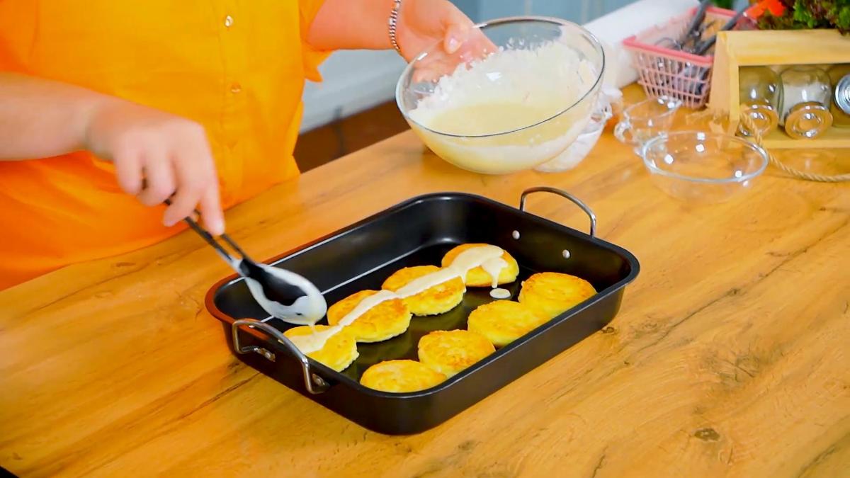 Обжаренные сырники в противне поливают сметанной заливкой