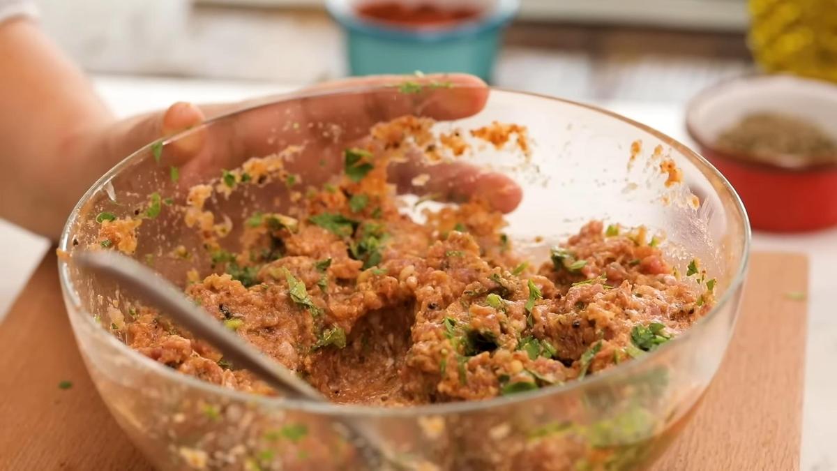 В стеклянной миске мясной фарш со специями и зеленью