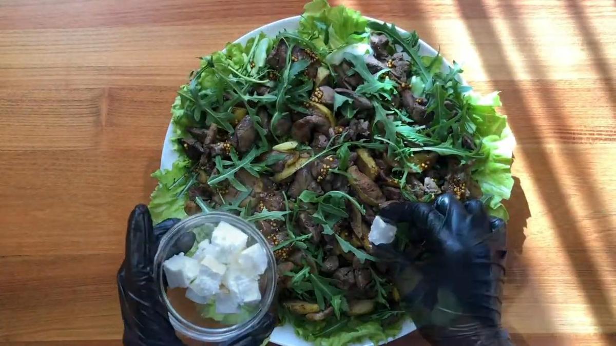 Салат с печенью, яблоками и зеленью на блюде