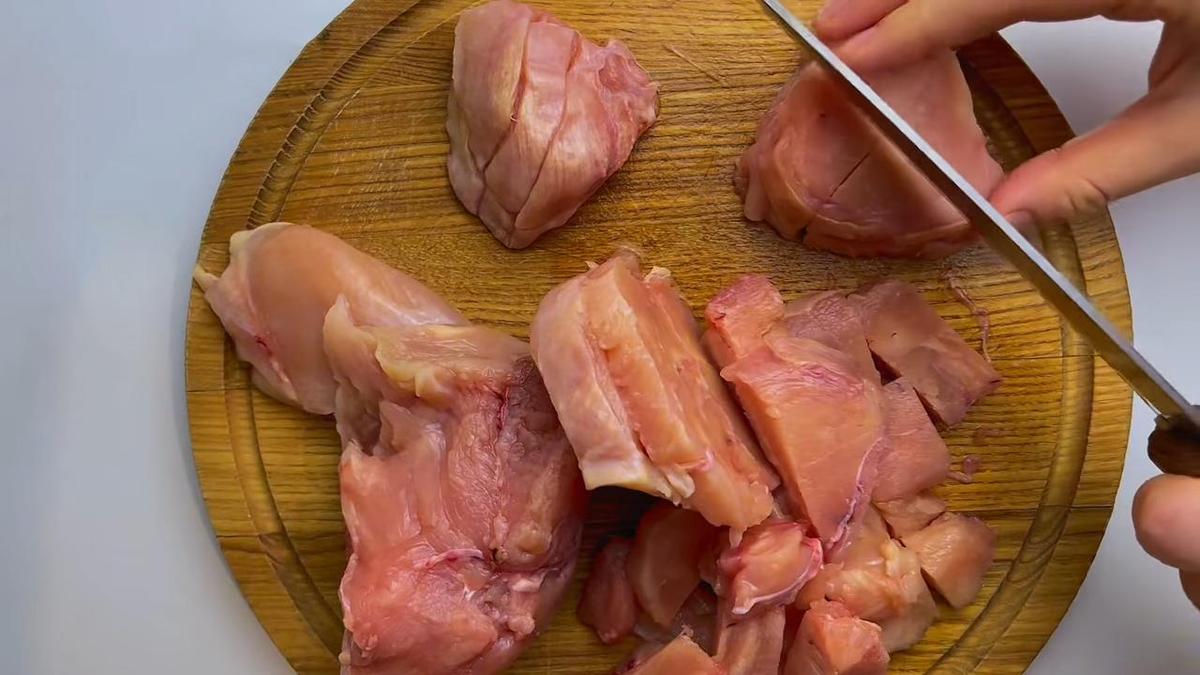 На разделочной доске нарезают куриную грудку