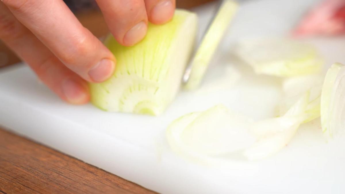 Лук нарезают на разделочной доске полукольцами