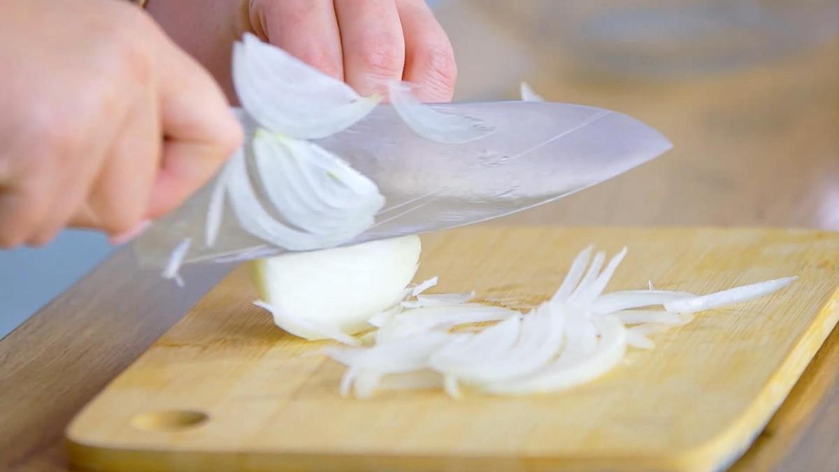 Лук нарезают на разделочной доске