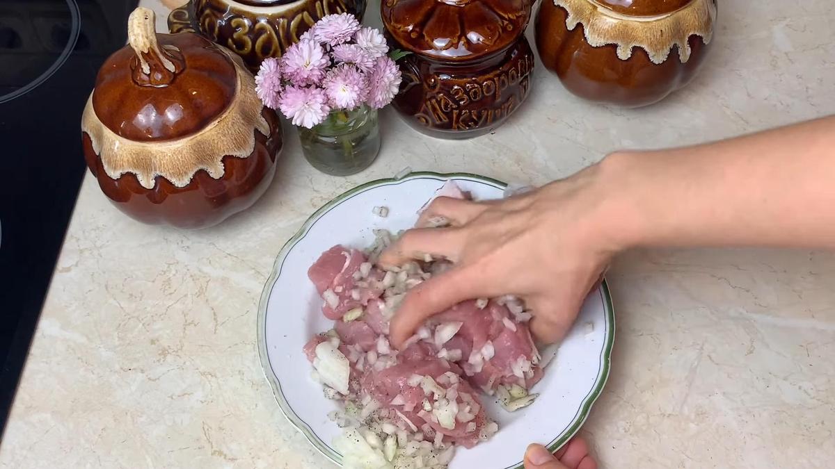 В тарелке рукой перемешивают кусочки свинины, лук и специи
