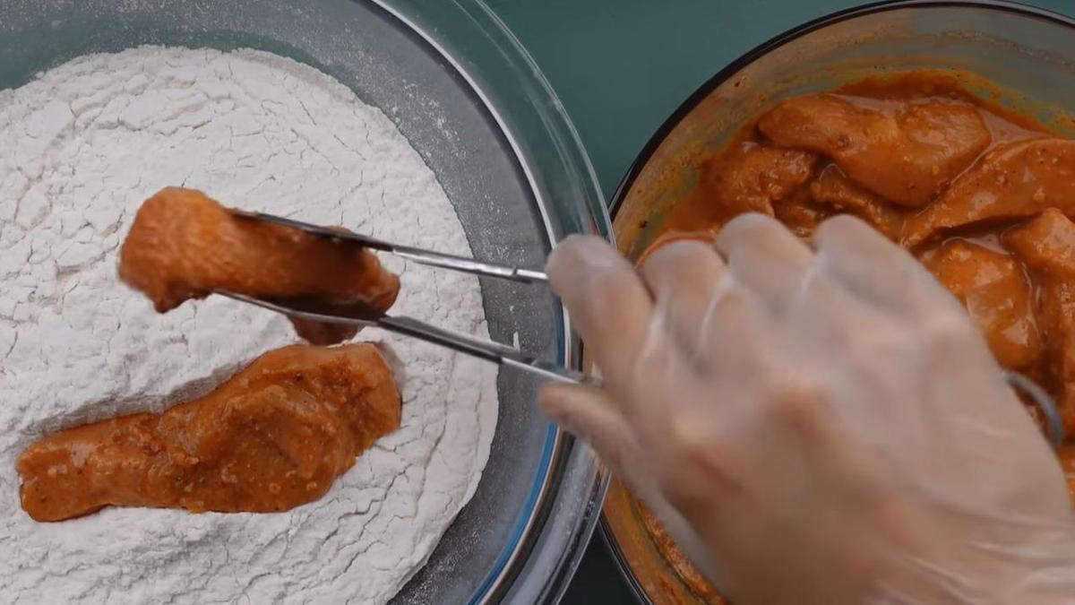 Стрипсы из куриного филе помещают в миску с мукой