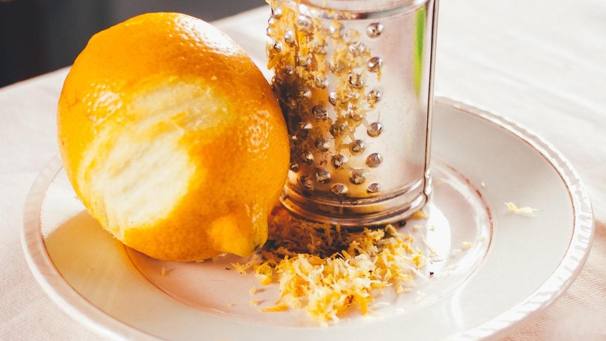 Лимон с частично снятой цедрой на фоне теркии белой тарелки