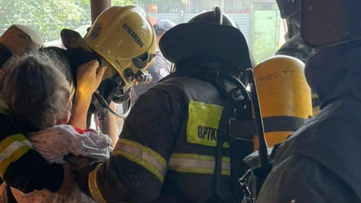 Пожарные выносят пожилую женщину из пожара Пожарные выносят пожилую женщину из пожара