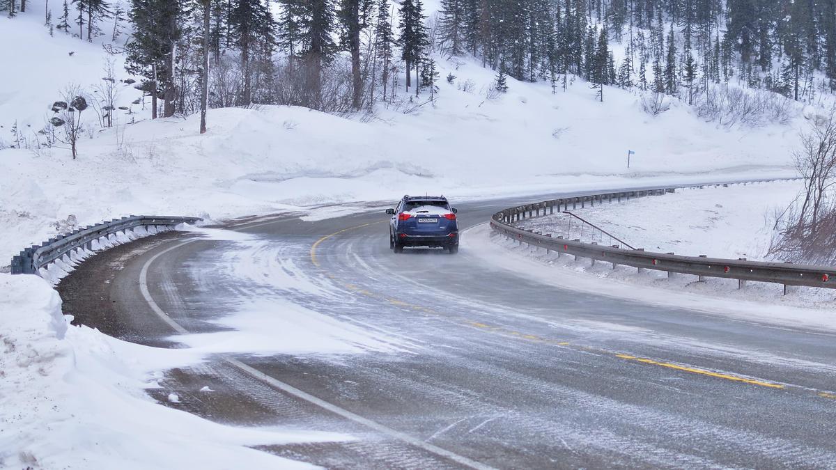 Автомобиль едет по заснеженной трассе