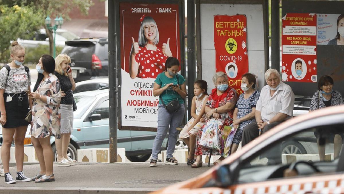 Люди в масках сидят на остановке