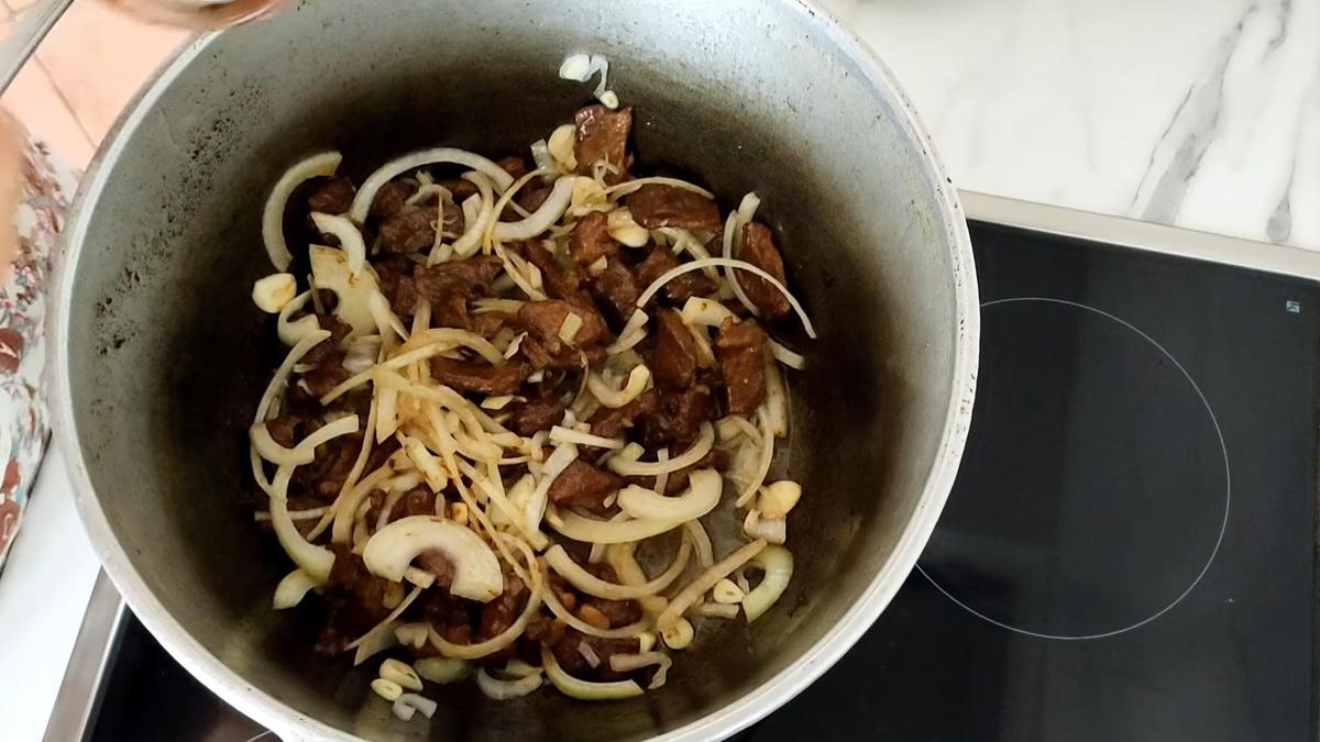В казане обжаренная баранина и нарезанный лук