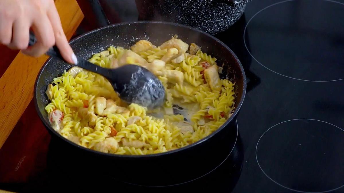 В сковороде перемешивают макароны, куриное филе и сливочный соус