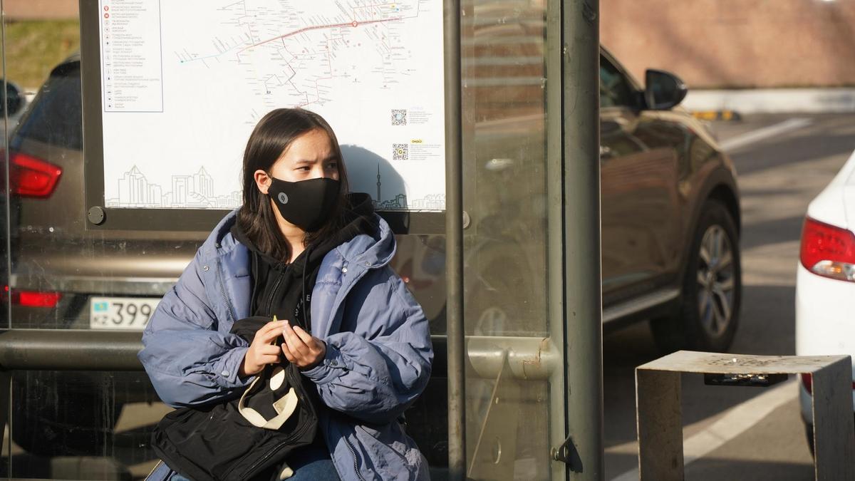 Девушка в маске на остановке