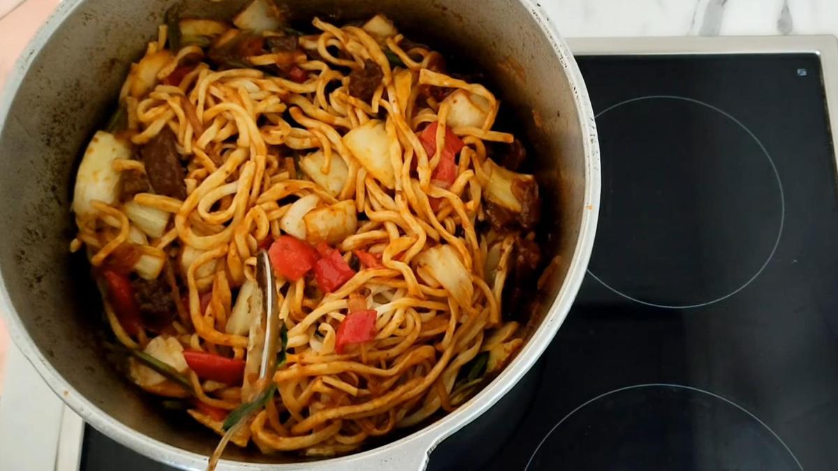 В казане смешивают лапшу, мясо и овощи