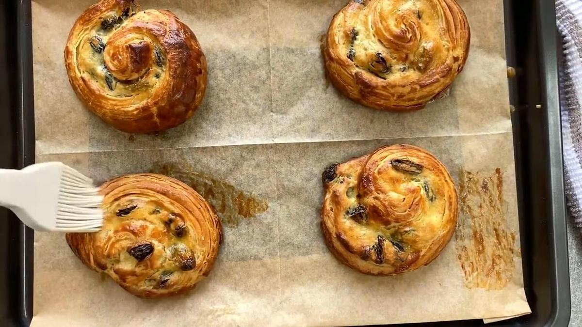 Готовые булочки с изюмом смазывают сахарным сиропом при помощи силиконовой кисточки