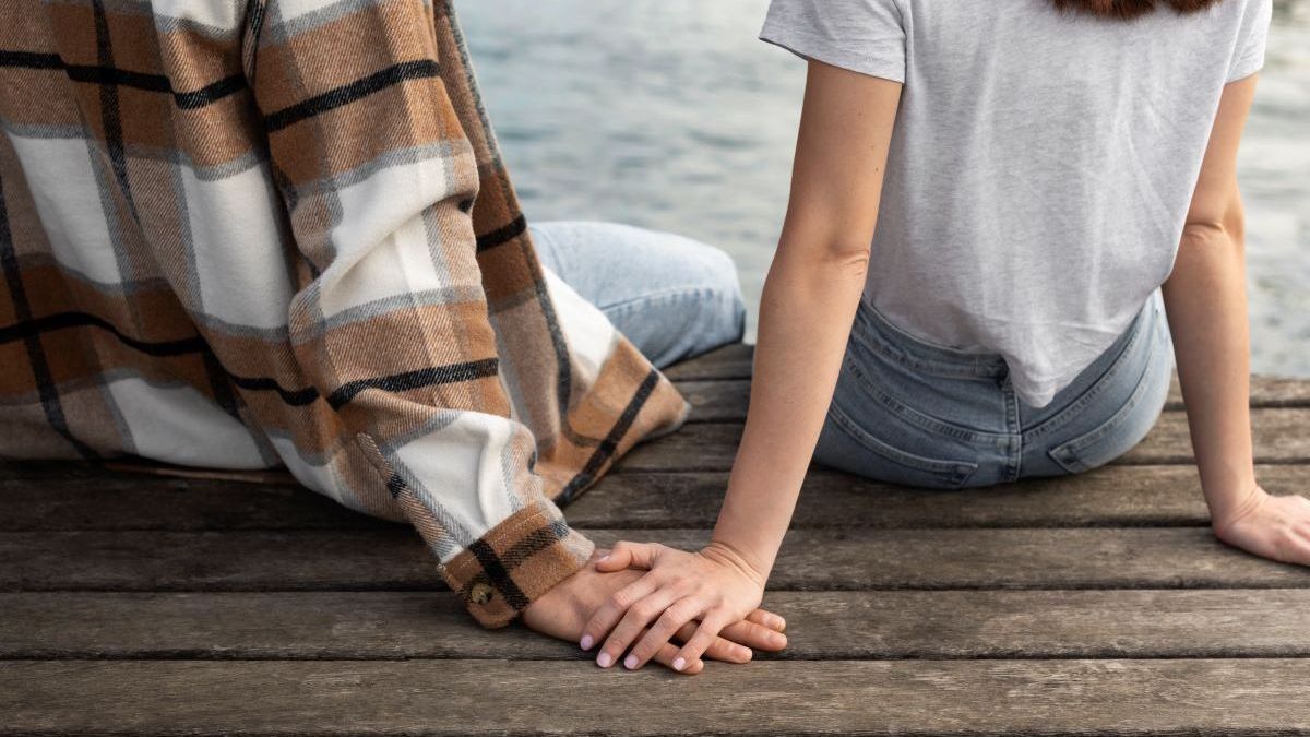 Парень с девушкой сидят у водоема