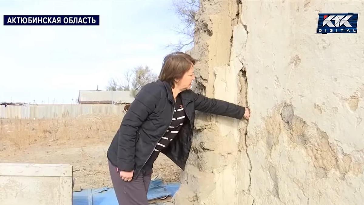 Женщина показывает аварийный дом