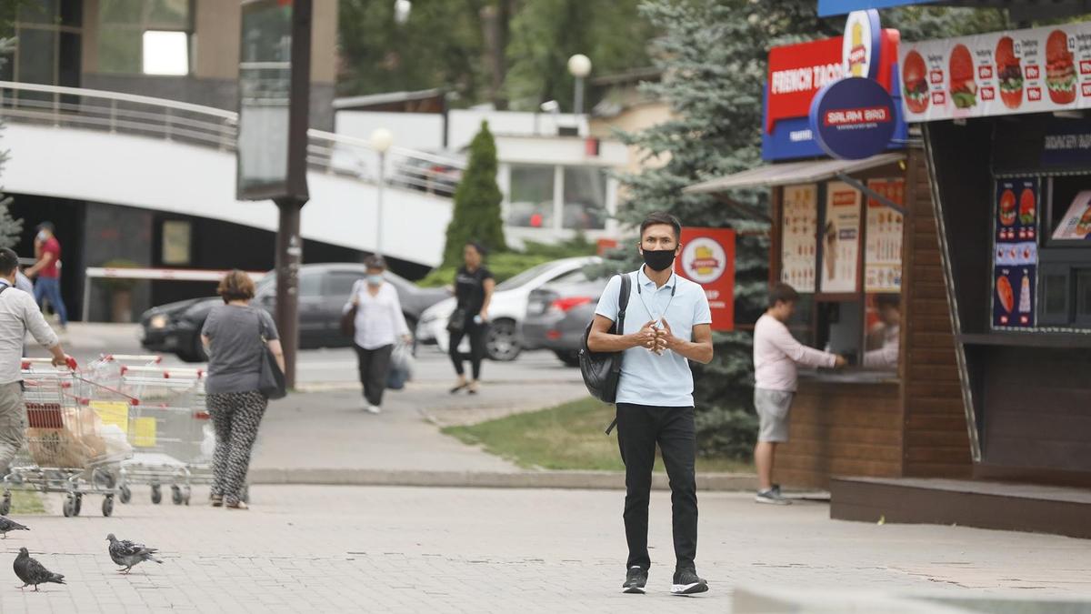 Парень в маске стоит возле киоска