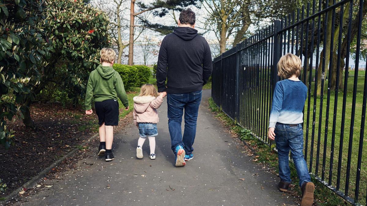 Мужчина идет с детьми по улице
