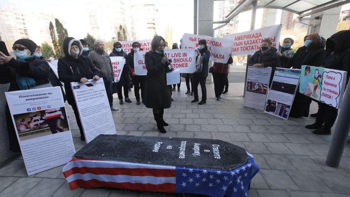 Люди с плакатами собрались вокруг гроба