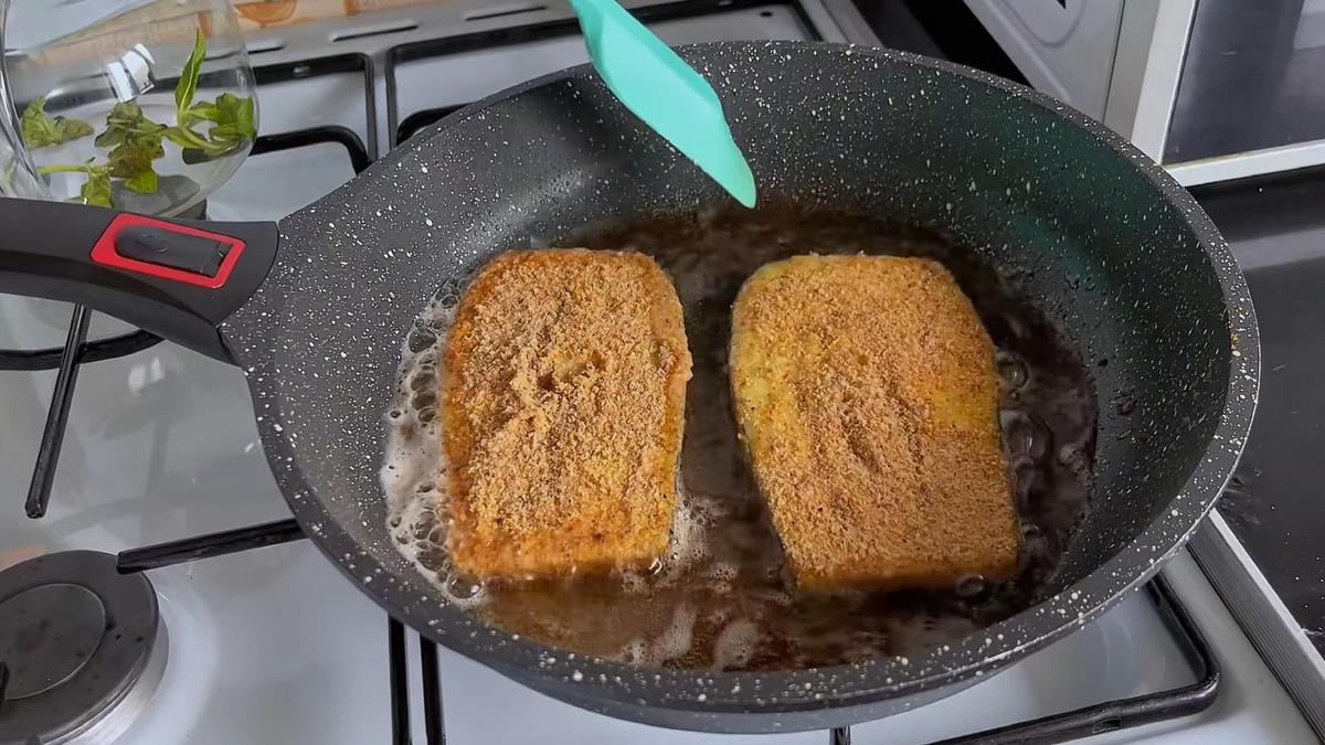 На сковороде жарятся слайсы баклажанов в кляре и панировочных сухарях