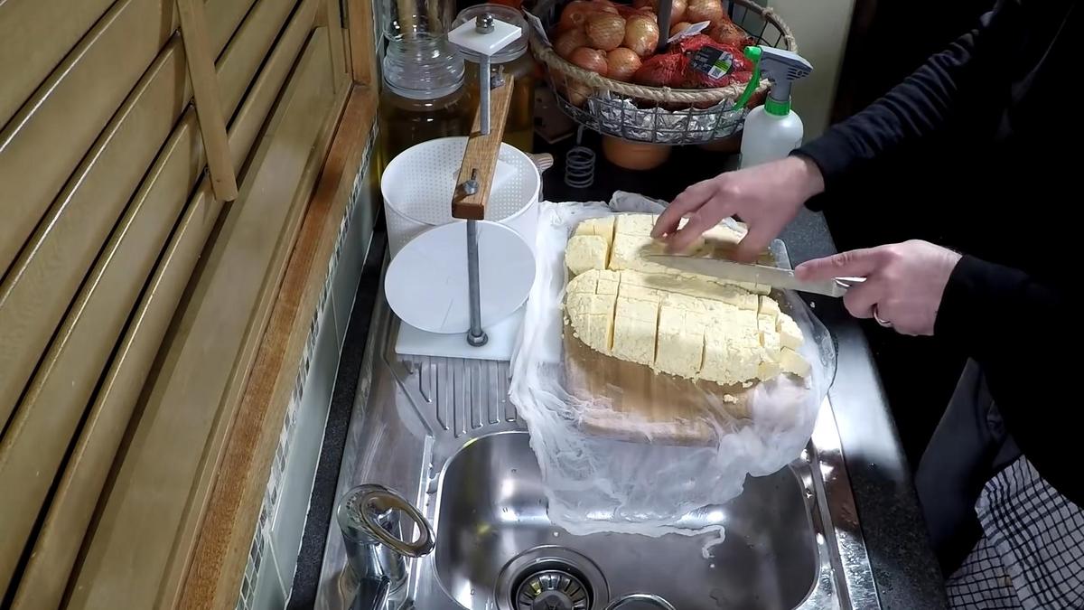 На разделочной доске нарезают сырную массу на кусочки