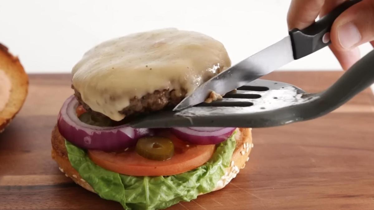 Котлету с сыром перекладывают на булочку с  салатным листом, огурцом,луком и помидором