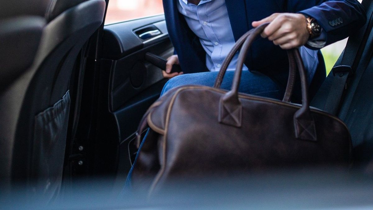 Человек с сумкой садится в машину