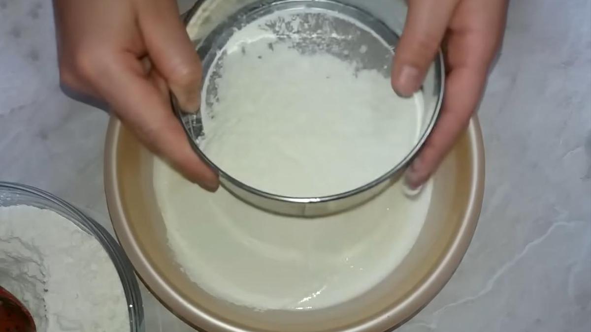 В миску с тестом просеивают муку