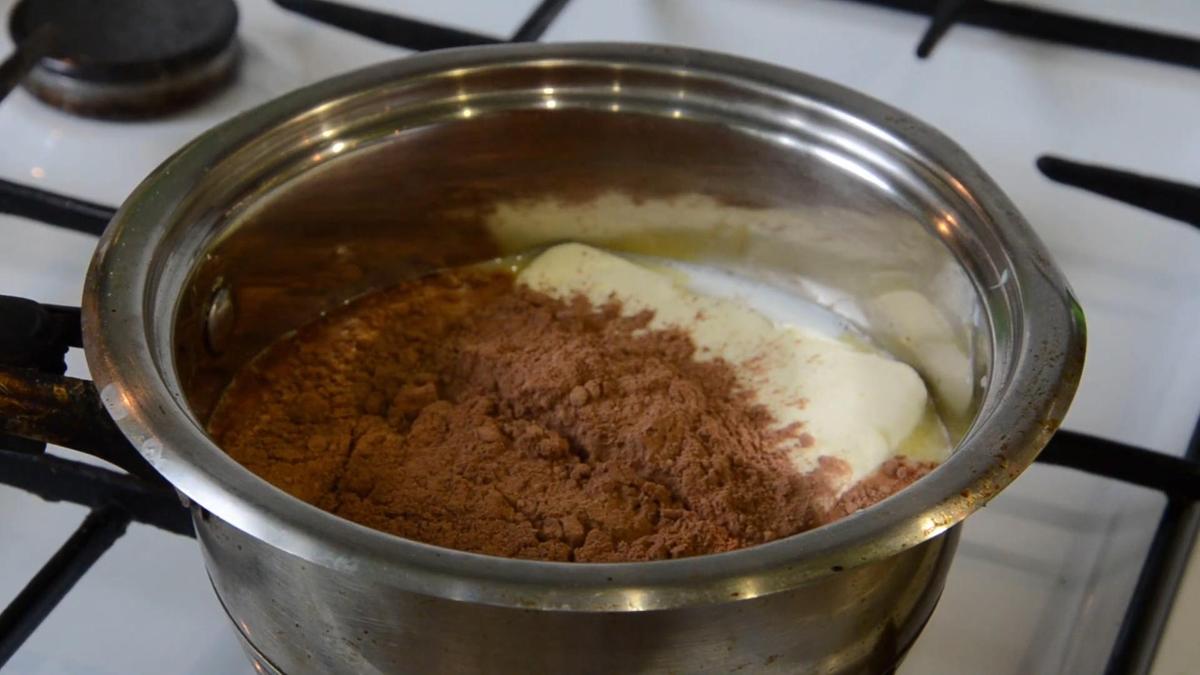Сотейник с молоком, какао, маслом и сахаром на плите