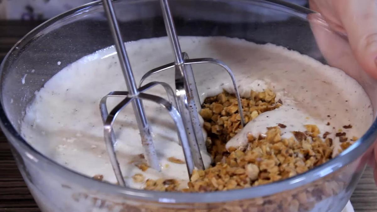 В стеклянной емкости миксером смешивают тесто с орехами
