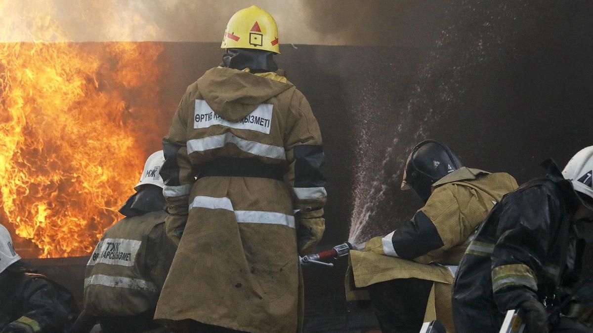 Несколько пожарных в защитной форме смотрят на огонь