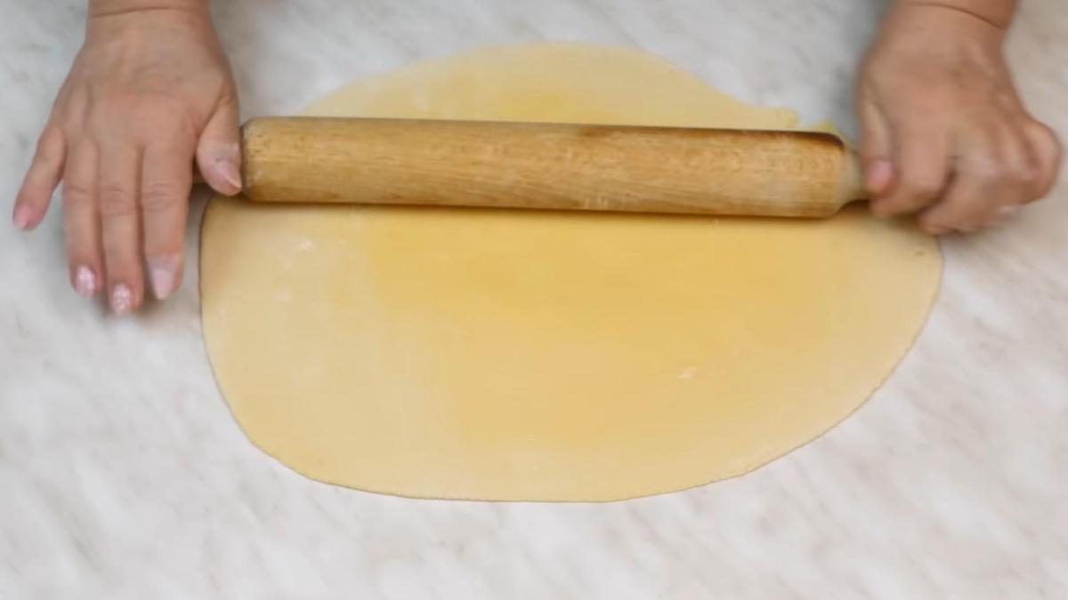 Раскатка теста скалкой на поверхности стола