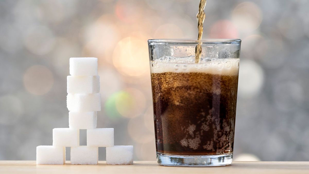 В стакан льется сахаросодержащий напиток