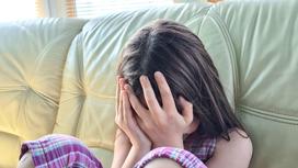 Девочка плачет на диване
