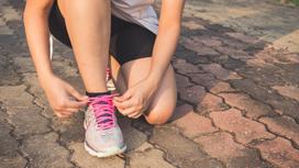 Девушка завязывает шнурок во время пробежки