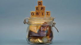 Деньги в баночке и кубики, выстренные в слово "Deposit".