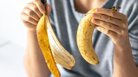 Женщина держит в руках целый банан и кожуру от банана