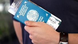 Мужчина держит в руках паспорт с авиабилетом