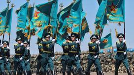 Военные в парадной форме шагают с поднятыми флагами