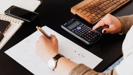 Женщина правой рукой считает на калькуляторе, а левой пишет на бумаге