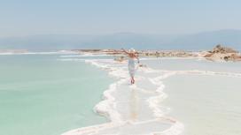Девушка в белом платье идет по побережью Мертвого моря