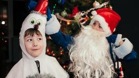 Дети в костюме снеговика и Деда Мороза под елкой