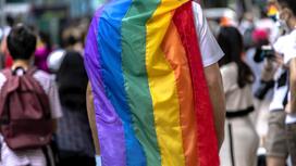 Человек с флагом ЛГБТ стоит на улице